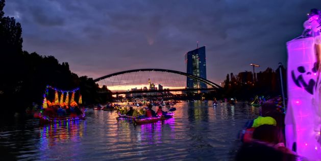 Schön iluminierte und geschmückte Boote in der Abenddämmerung vor der eindrucksvollen Skyline von Frankfurt